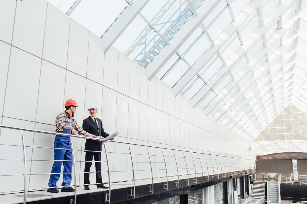 Standing industrial engineers in blue vests and helmets. Glass r